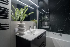 Łazienka z umywalką, ozdobną wazą i czarnymi marmurowymi płytkami w realizacji Skrajna w Warszawie